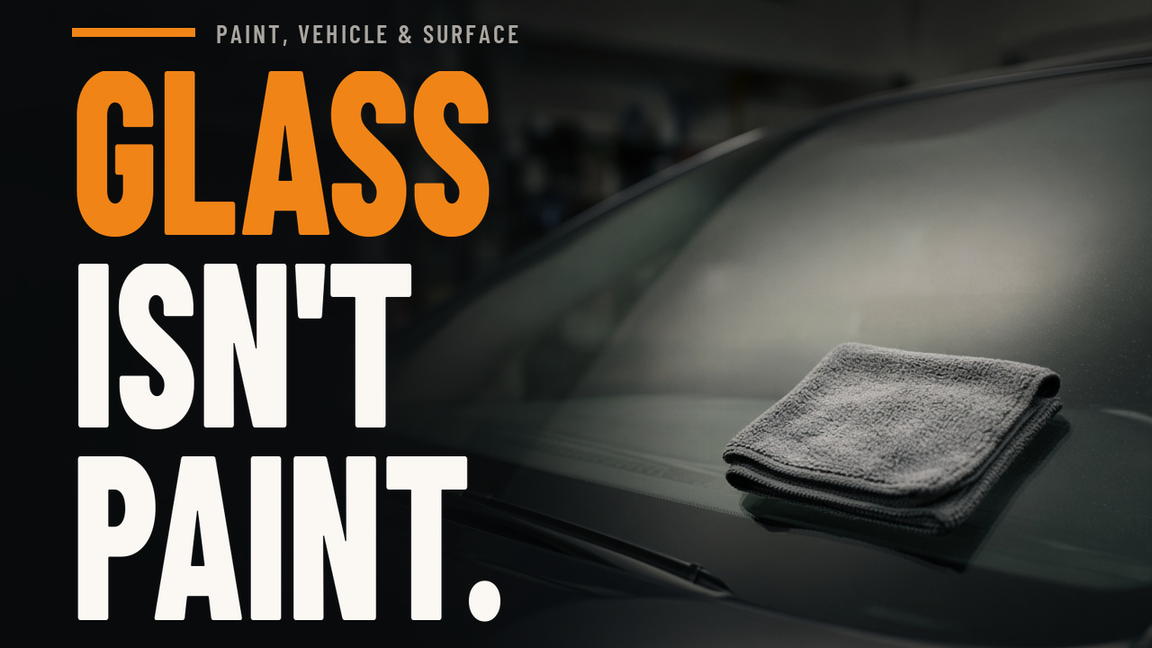 Folded microfiber towel resting on a clean, dry windshield in a dim garage